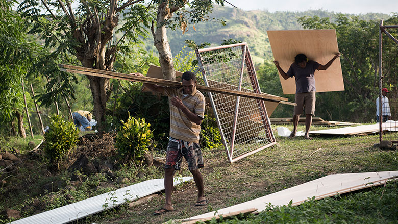 People from Namarai unload construction materials for new homes in the village. (Alana Holmberg/World Bank)