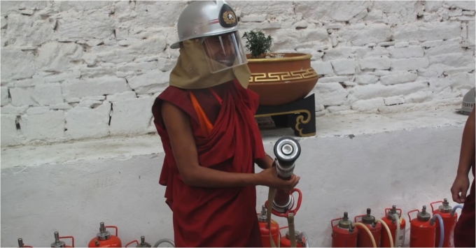 A monk learns to use a fire extinguisher hydrant.