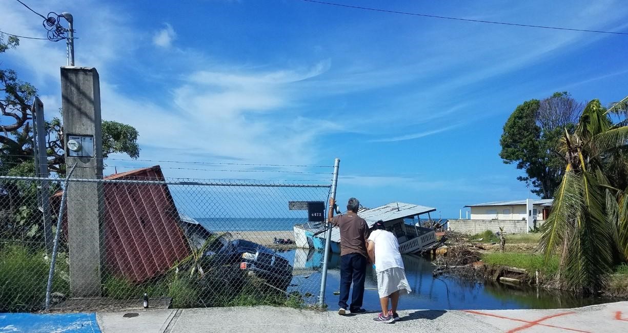 two people survey wreckage after a hurricane in the caribbean