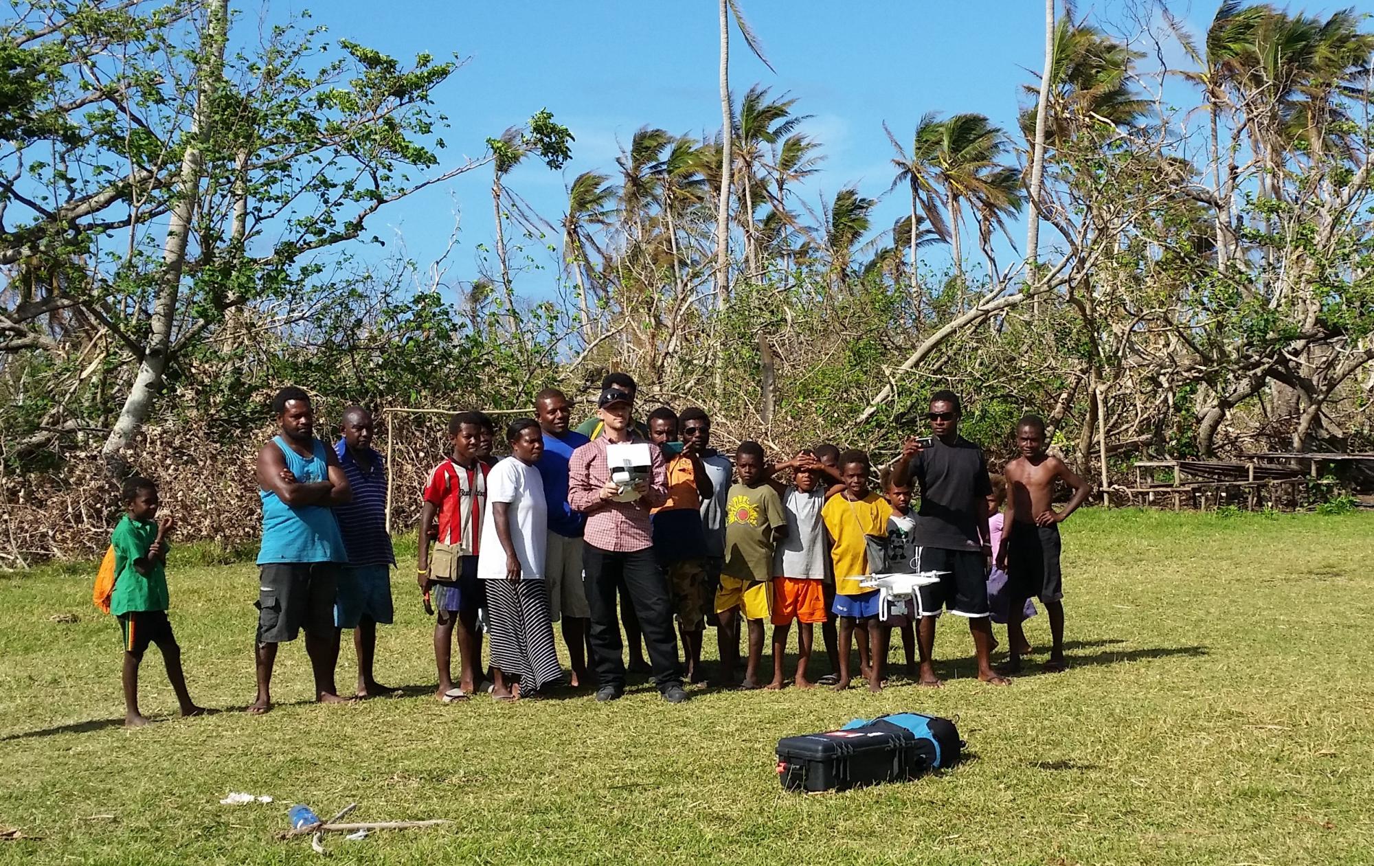 A group of children watch as some of them control drones, which will be used to take aerial photos for risk mapping.