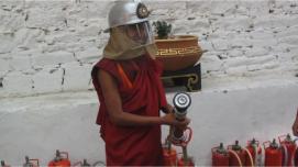 A monk learns to use a fire extinguisher hydrant.