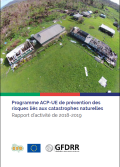 Aerial view of two school buildings with damaged roofs surrounded by debris from an extreme weather event.